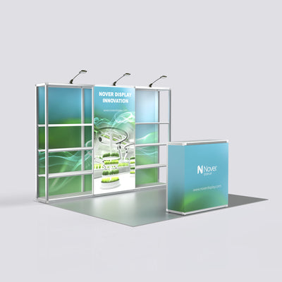 10ft modular exhibition booth display featuring a 3-section aluminum shelving backdrop with blue-green graphic panels, spotlights, and a matching front counter on a light gray background.